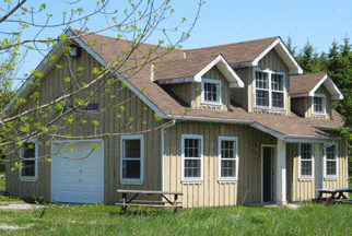 Field Centre Large wooden building with several windows, man door and garage door.