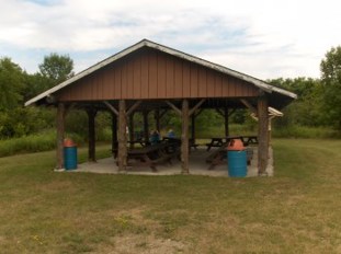 Group Camp Brown wooden pavilion with several picnic tables and garbage cans.